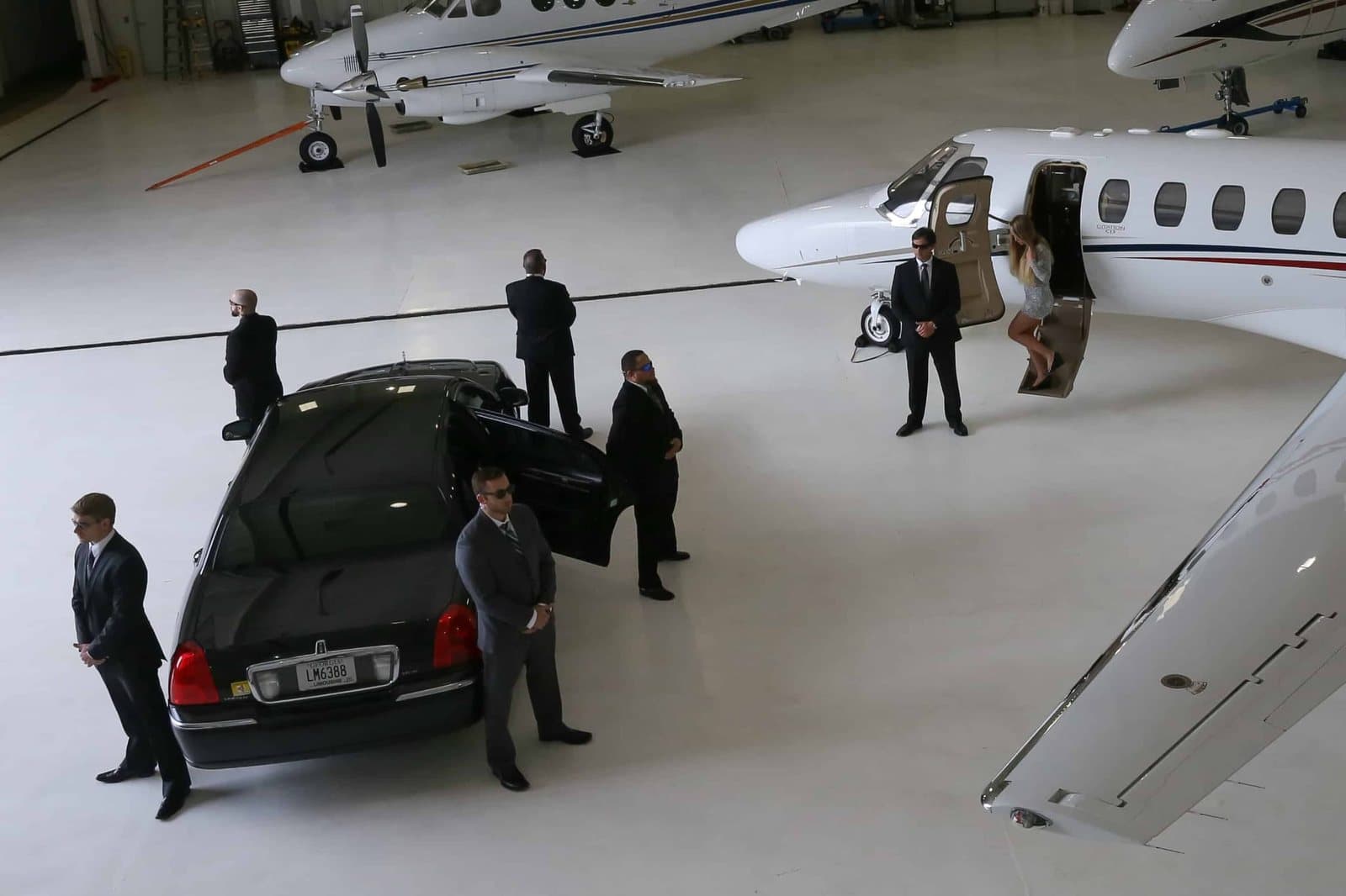 A close protection team holding position around a principal’s vehicle and aircraft